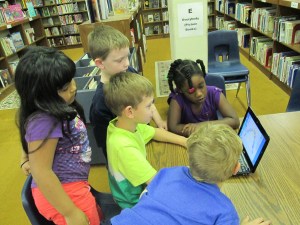 Students gathered around the netbook to plan out what they would share on the screencast.